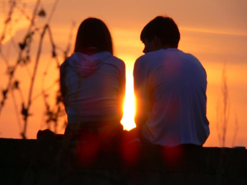хлопець і дівчина сидять при заході сонця